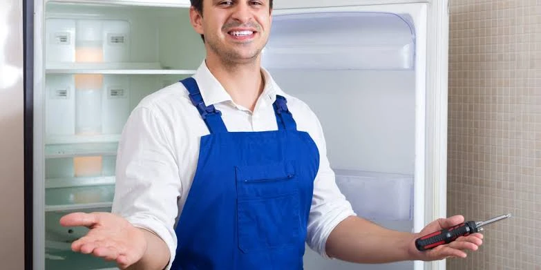 Technician holding a screwdriver in front of an open refrigerator