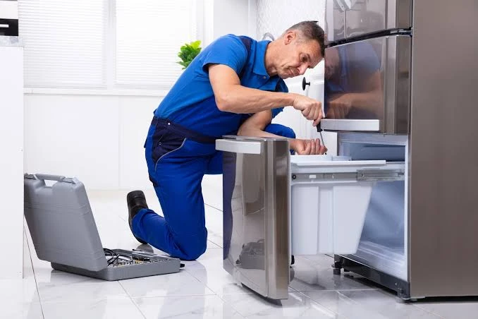 Technician in blue workwear repairing a refrigerator freezer drawer