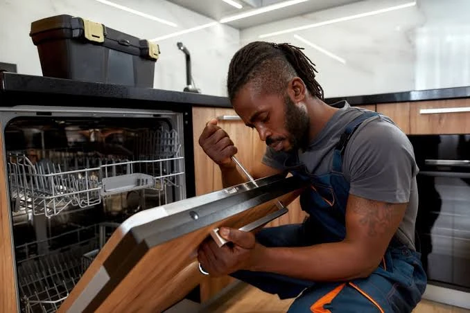 Technician using a screwdriver to inspect an open dishwasher door