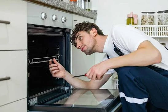 Technician examining the interior and door of a built-in oven